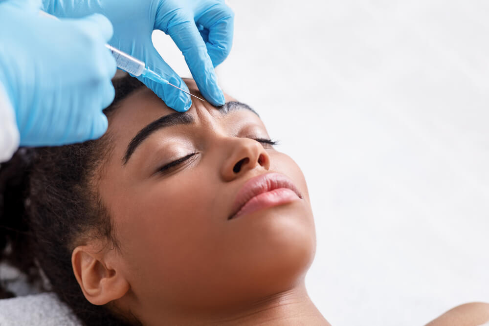 Young African Woman Receiving Botox Injection in Interbrow Zone at Beauty Clinic